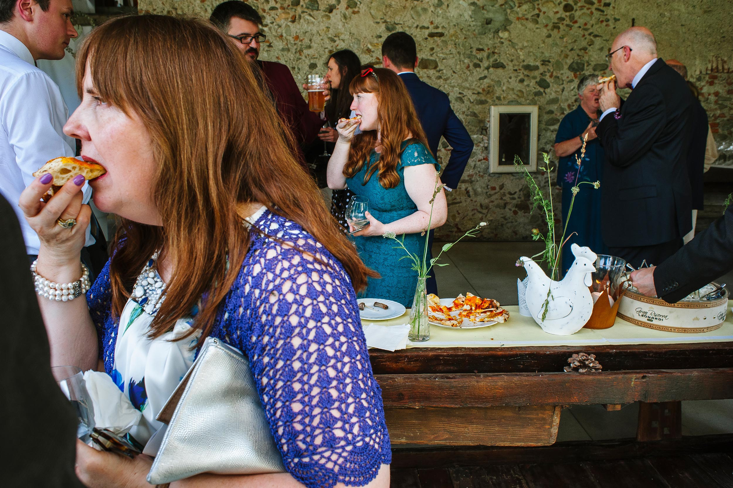 three guests at wedding eating pizza slices at the same time