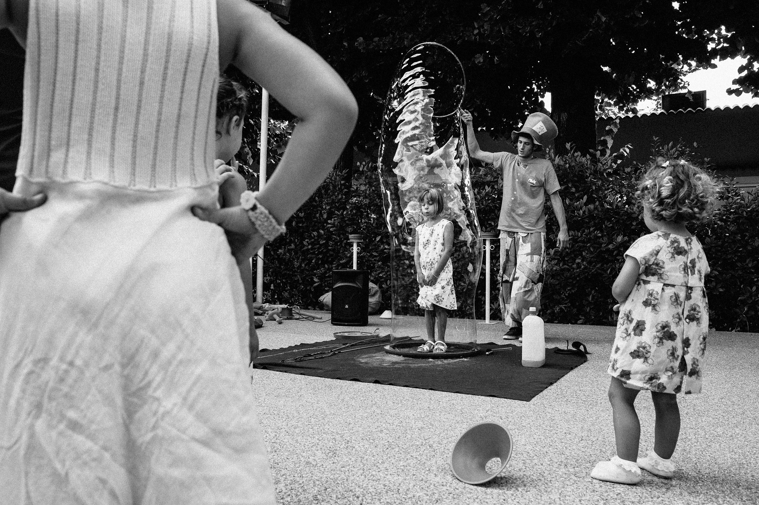 children watching a girl in a tunnel of soap ball black and white wedding photography
