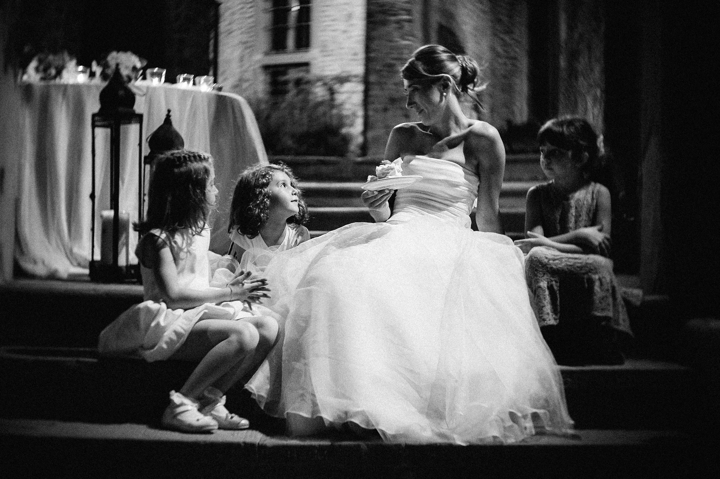 girls around the bride relaxed moment eating cake black and white wedding photography