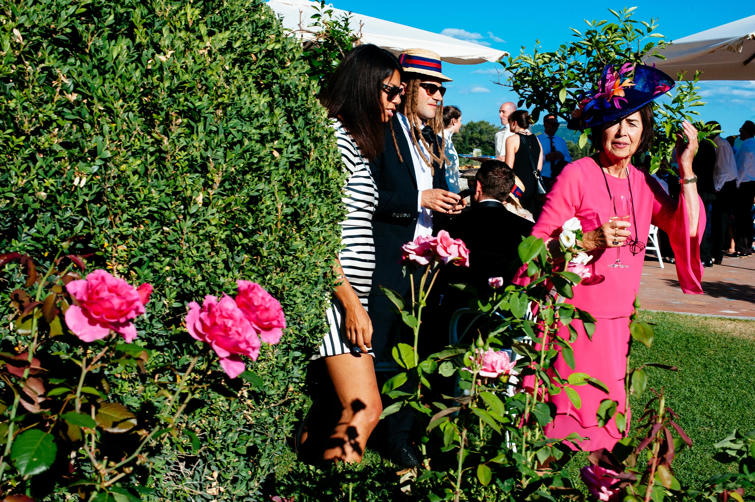lady dressed in magenta next to magenta roses at reception documentary street wedding photography by Alessandro Avenali