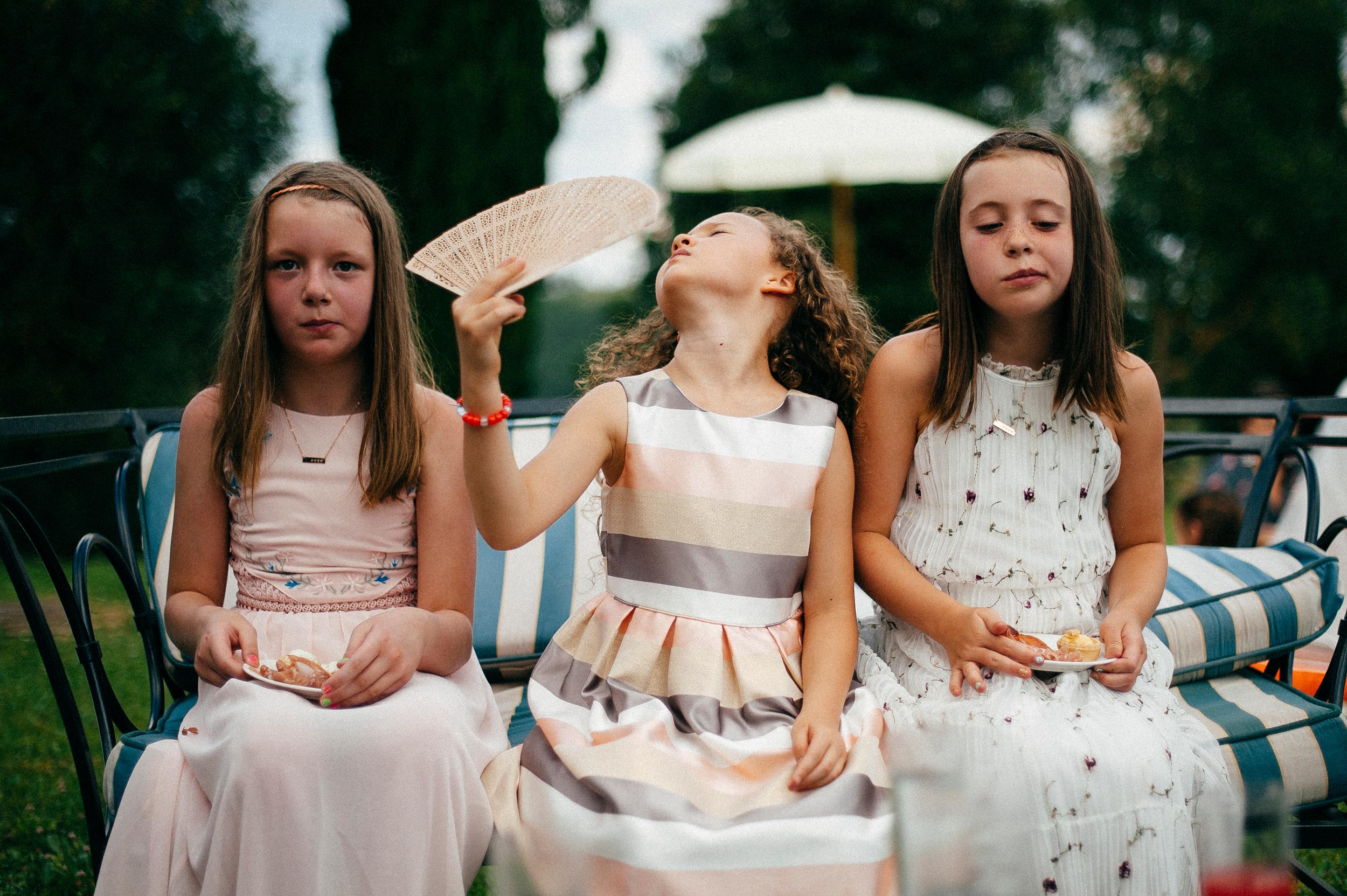 girls at the reception using fan hot weather documentary wedding photography in tuscany by Alessandro Avenali