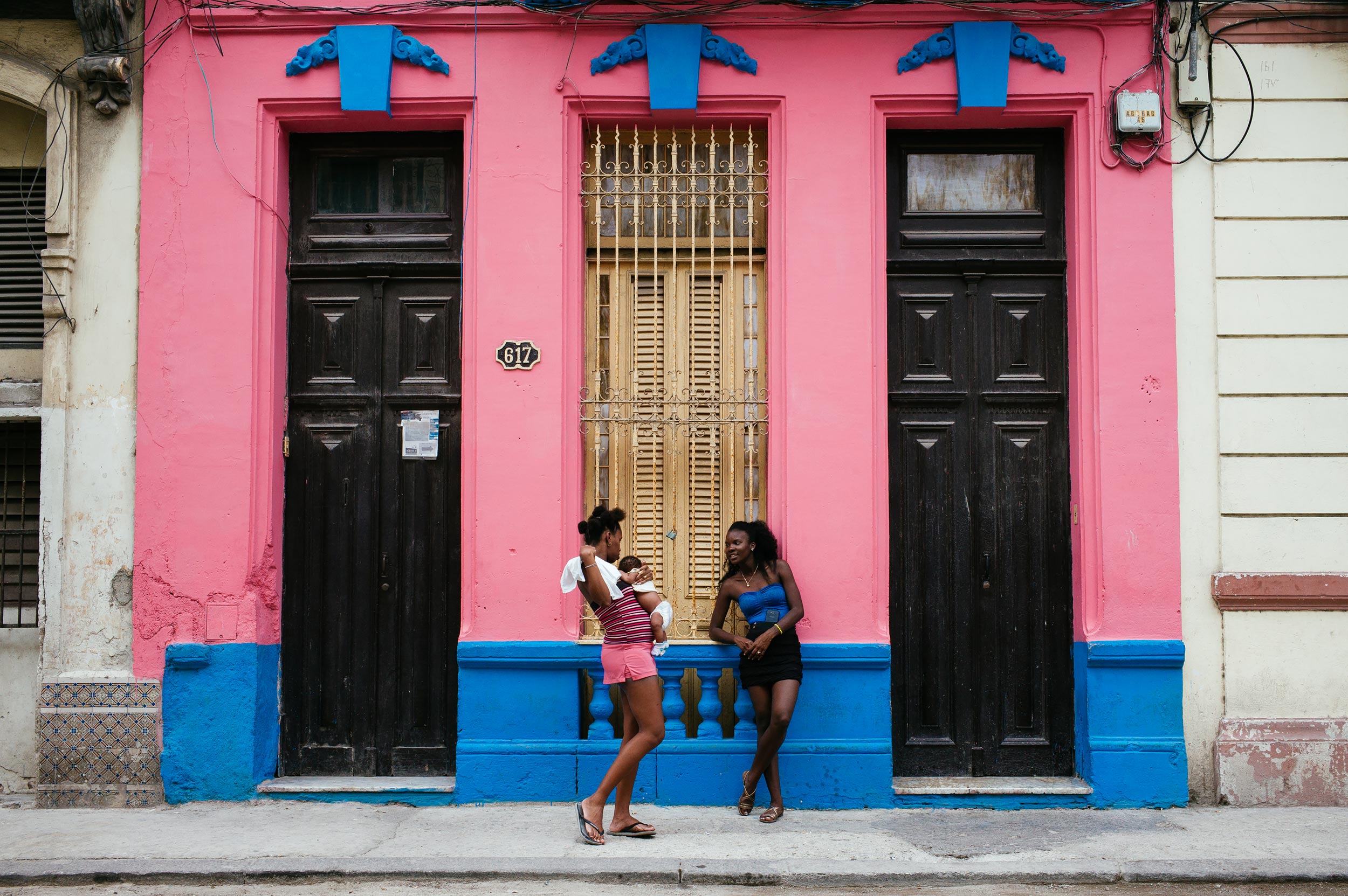 La Habana 2016 - Two ladies standing, building has colors of their clothes