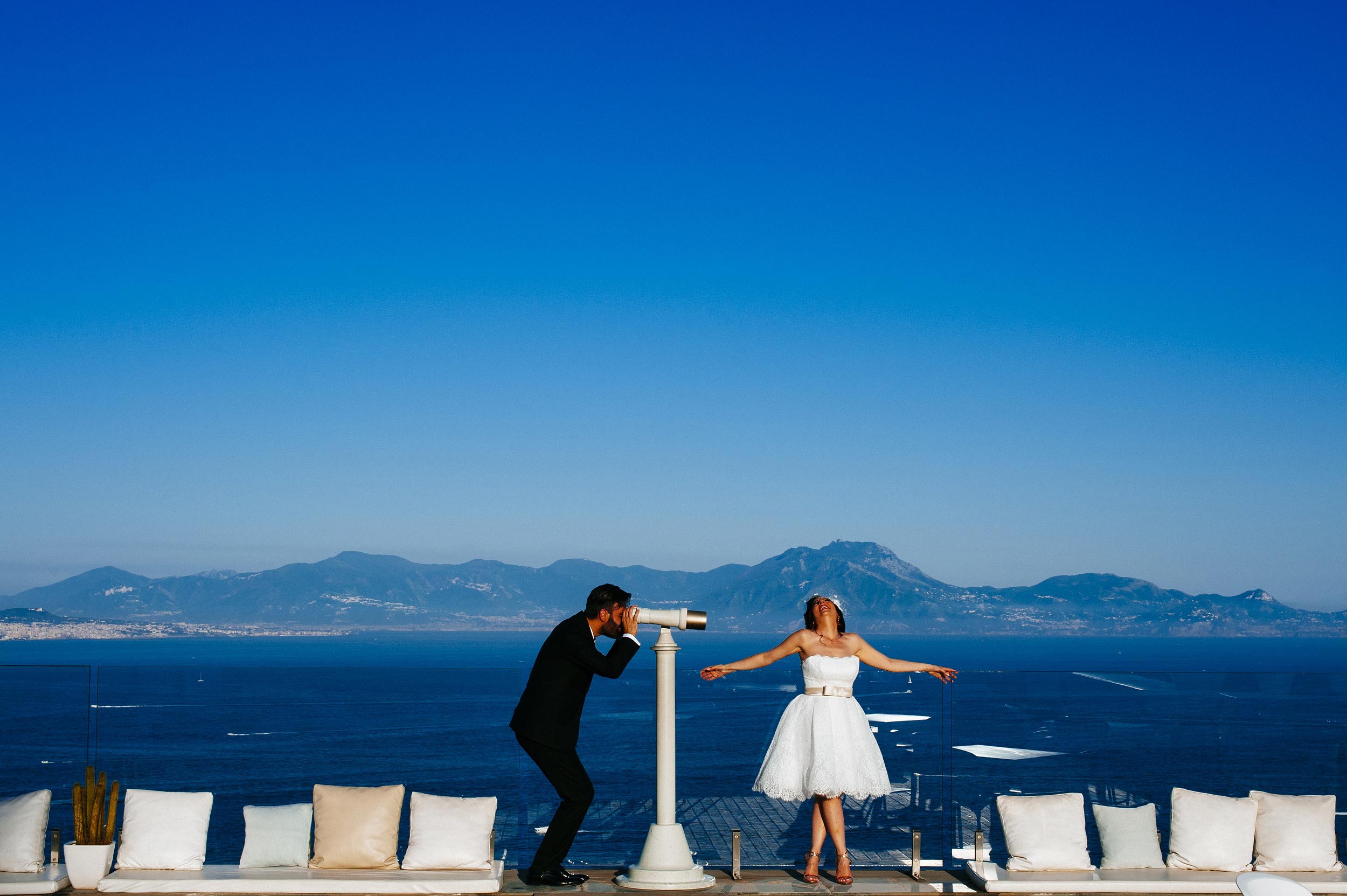 wedding naples terrace over the sea groom watching bride through spyglass by Alessandro Avenali